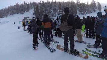 pov eines Snowboarders und Skifahrers, die in einer Liftlinie in einem Skigebiet stehen. video