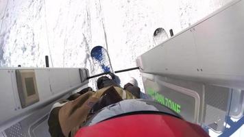 pov de snowboarders andando em um elevador em uma estação de esqui.