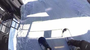 Standpunkt von Snowboardern, die auf einem Lift in einem Skigebiet fahren.