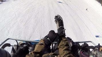 Standpunkt von Snowboardern, die auf einem Lift in einem Skigebiet fahren.