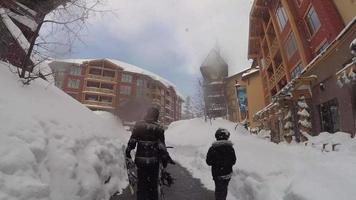 pov de uma família caminhando com suas pranchas de snowboard em uma estação de esqui. video