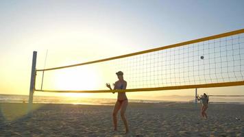 las jugadoras juegan voleibol de playa y una jugadora sirve golpeando a su compañero en la cabeza con la pelota.