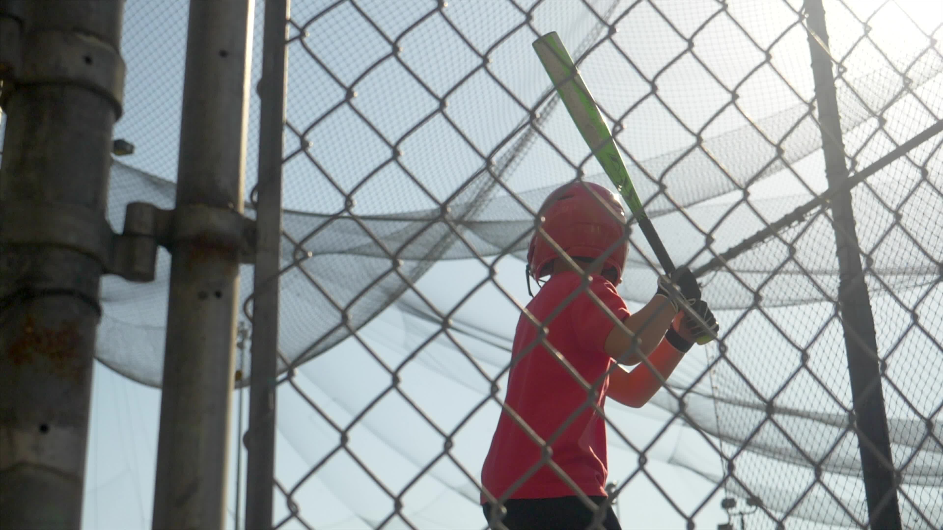 A boy practices little league baseball at the batting cages and bunting