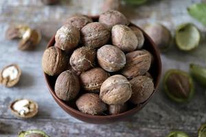 Walnuts in a bowl. Walnut leaves Walnuts in a green peel photo