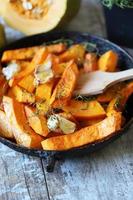 Baked pumpkin slices in a pan with herbs and garlic photo