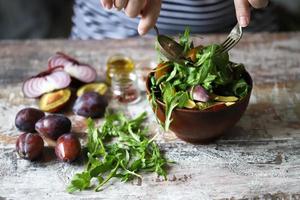 Healthy salad mix male hands with a spoon and fork. Arugula plum salad. photo