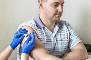 un médico vacuna a un hombre contra el coronavirus en una clínica. de cerca. el concepto de vacunación, inmunización, prevención contra covid-19.