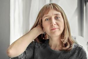 Portrait of a young woman by the window in neutral colors photo