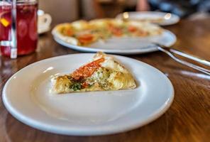 una rebanada de pizza vegetariana en un plato blanco. mesa servida en un restaurante italiano foto
