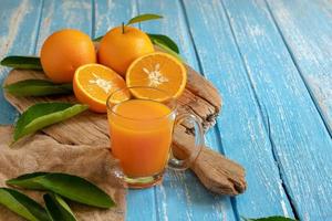Fresh orange and a glass of orange juice on a wooden table background photo