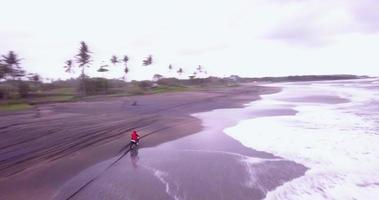 Aerial drone view of a man riding his motocross motorcycle on the beach. video