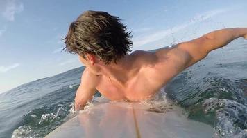 POV of a surfer paddling and surfing waves on his surfboard.