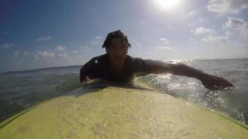 pov di un surfista che rema e surfa le onde sulla sua tavola da surf. video