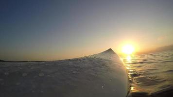 pov på en surfbräda i havet vid solnedgången. video