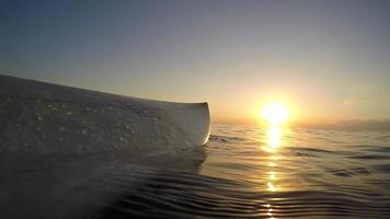 pov van een surfplank in de oceaan bij zonsondergang.