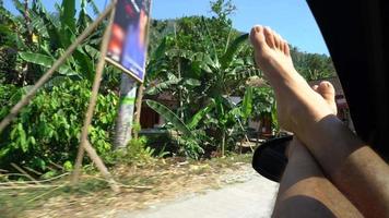 POV of a man with his feet out the window of a car in Indonesia. video