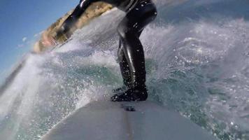POV of a surfer surfing waves on his surfboard in a full wetsuit. video