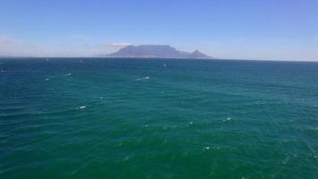 Luftreisedrohnenansicht des Tafelbergs und der Tafelbucht und Kiteboarder von Bloubergstrand, Kapstadt, Südafrika. video