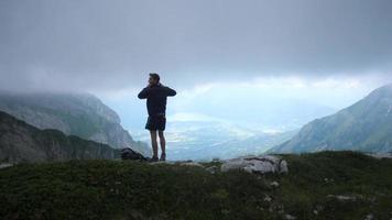 um homem tira uma foto da vista durante uma caminhada nas montanhas. video