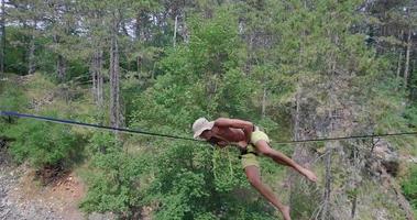 un hombre intenta mantener el equilibrio y cae mientras se afloja en una cuerda floja. video