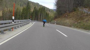 een skateboarder die downhill skateboarden op een snelweg in de bergen. video