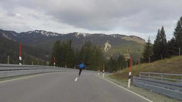een skateboarder die downhill skateboarden op een snelweg in de bergen. video