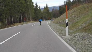 un patinador en patineta cuesta abajo en una carretera de montaña.