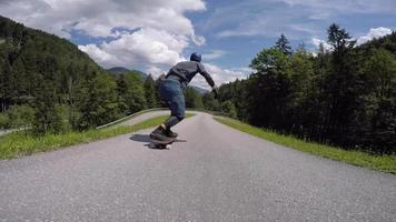un patinador que corre cuesta abajo en monopatín en una carretera de montaña. video