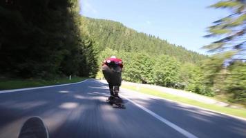 un patinador que corre cuesta abajo en monopatín en una carretera de montaña. video