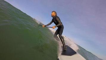 pov de um homem sup standup paddleboard surfando em uma onda.