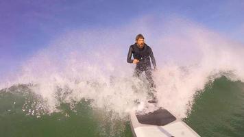pov de um homem batendo wipeout em um sup stand up paddleboard surfando em uma onda. video