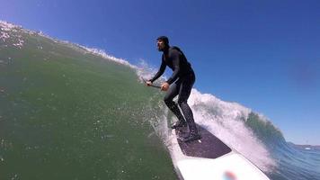 pov de um homem sup stand up paddleboard surf em uma onda.