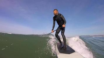 pov de un hombre chocando wipeout en un sup stand up paddleboard surfeando en una ola.