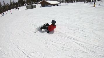 un niño snowboarder haciendo snowboard y cayendo en una estación de esquí. video