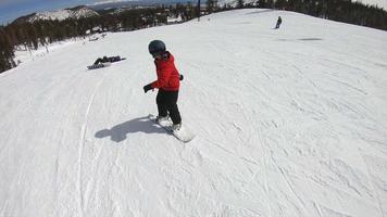 un niño snowboarder haciendo snowboard y cayendo en una estación de esquí. video