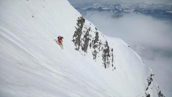 ein Skifahrer, der einen steilen Berg im Schnee hinunterfährt. video