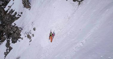 Aerial drone view of a mountain climber climbing up with crampons in the snow. video