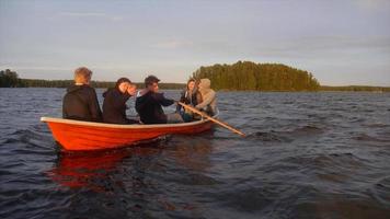 jovens adultos correndo e remando um barco em um lago ao pôr do sol.