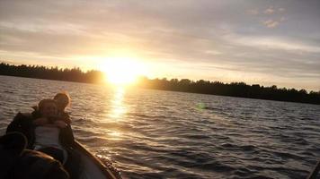jovens adultos correndo e remando um barco em um lago ao pôr do sol.