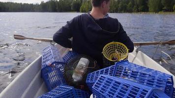 jovens adultos pescando com armadilhas de rede em um pequeno barco a remo em um lago. video