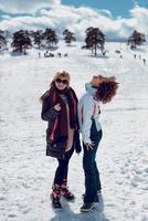 dos mujeres felices de pie y divirtiéndose en la nieve en el soleado día de invierno. foto