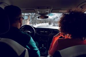 una pareja conduce en el elegante coche en un día nevado de invierno.