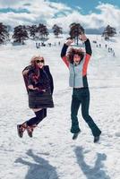 Two happy women jumping in the air and having fun at snow on the sunny winter day. photo