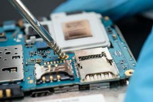 Technician repairing inside of mobile phone by soldering iron. Integrated Circuit. the concept of data, hardware, technology. photo