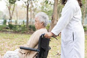 Médico ayuda y cuidado paciente asiático mayor o anciana mujer sentada en silla de ruedas en la sala del hospital de enfermería, concepto médico fuerte y saludable foto