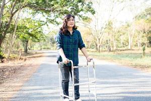 Asia dama de mediana edad mujer paciente caminar con andador en el parque foto