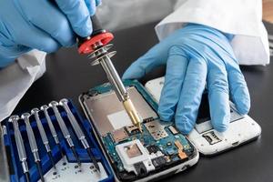 Technician repairing inside of mobile phone by soldering iron. Integrated Circuit. the concept of data, hardware, technology. photo