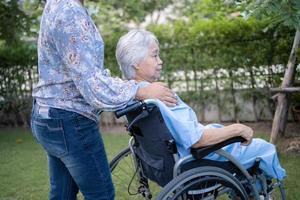 médico ayuda y cuidado paciente asiático mayor o anciano mujer sentada en silla de ruedas en el parque en la sala del hospital de enfermería, concepto médico fuerte y saludable. foto