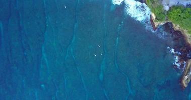 vue aérienne de drones de surfeurs surfant sur un récif de corail et des vagues à la plage. video