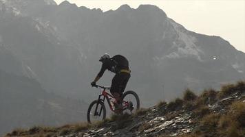 Silhouette of a mountain biker riding downhill on a trail in the mountains. video